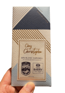 A hand holding a CTS chocolate bar. Wrapper has the Cooks' Camp and Cacao Barry logo.
