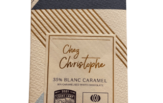 A hand holding a CTS chocolate bar. Wrapper has the Cooks' Camp and Cacao Barry logo.